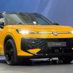 Żółty Volkswagen T-Roc z czarnym dachem i felgami. Zbliżenie na przód auta, gdzie widoczne są światła LED i atrapa chłodnicy. T roc wymiary sugerują kompaktowy SUV.
