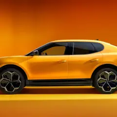 Żółty Ford Capri 2025, sportowy SUV z futurystycznym designem, prezentuje się na tle pomarańczowego gradientu.