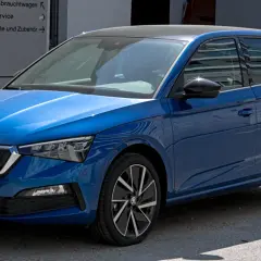 Błękitna Skoda Scala z czarnym dachem, zaparkowana przed budynkiem z napisem "Gebrauchtwagen".