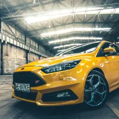 Żółty Ford Focus MK3 1.6 benzyna ST w hangarze, gotowy do jazdy.
