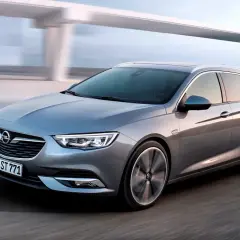 Srebrne kombi z charakterystycznymi insygniami marki Opel pędzi po drodze.