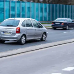 Srebrny Citroën Xsara Picasso jedzie po drodze, obok niebieski sedan.
