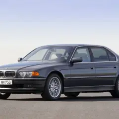 Ciemnoszary sedan BMW serii 7 (E38) z silnikiem V12 na tle nieba.