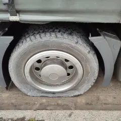 Płaska opona ciężarówki pod błotnikiem.