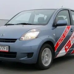 Niebieski Daihatsu Sirion z napisem "AUTO CLUB DAIHATSU" na boku, jadący po drodze.