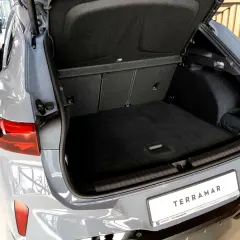 Otwarty bagażnik szarego SUV-a Cupra Terramar z widocznym wnętrzem i tablicą rejestracyjną.