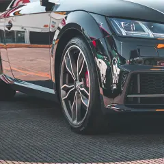Zbliżenie na czarne, sportowe auto z felgami i oponami.