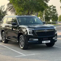 Czarny Nissan Patrol 2025 zaparkowany na tle drzew i palmy.