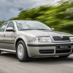 Srebrna Škoda Octavia jedzie po drodze, otoczona rozmytą zielenią. Sprawdź atrakcyjną Škoda Octavia cenę!