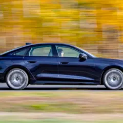 Ciemnoniebieskie Audi A4 B10 w ruchu, z rozmytym tłem jesiennych drzew.