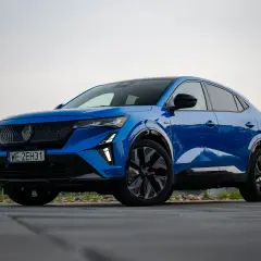 Niebieski Renault Rafale, SUV coupe, zaparkowany na drewnianym tarasie.