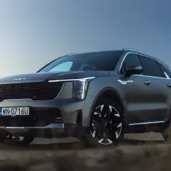 Szary SUV Kia Sorento na tle pustynnego krajobrazu o zachodzie słońca.