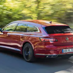 Czerwony Volkswagen Arteon Shooting Brake w ruchu na tle rozmytego krajobrazu.