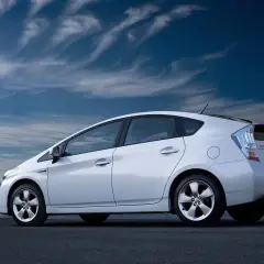 Biały Toyota Prius 3 na tle błękitnego nieba z chmurami.