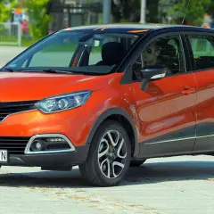 Pomarańczowy Renault Captur 2015 z czarnym dachem i pomarańczowymi akcentami, zaparkowany na placu.
