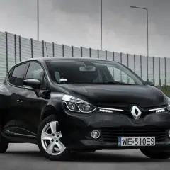 Czarny Renault Clio IV na drodze, z barierą dźwiękochłonną w tle.