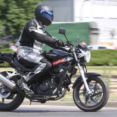 Motocyklista w pełnym stroju pędzi na czarnym Hyosung GT 125, ciesząc się jazdą.