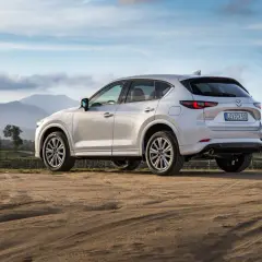 Biała Mazda CX-5 na tle gór i nieba. Elegancki SUV gotowy na przygodę.