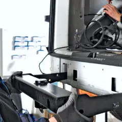 Uśmiechnięty mechanik z rękawicami montuje hak holowniczy do samochodu.