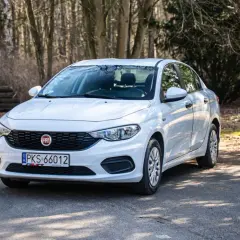 Biały Fiat Tipo sedan zaparkowany na leśnej drodze.