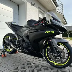 Czarny motocykl Yamaha R3 z neonowymi żółtymi akcentami, gotowy do jazdy.