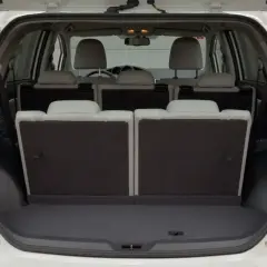 Biała Toyota Verso 1.8 benzyna z otwartym bagażnikiem. Tylne siedzenia złożone, tworząc dużą przestrzeń bagażową.