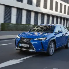 Niebieski Lexus UX 300e w ruchu miejskim. Kompaktowy SUV, którego lexus ux wymiary idealnie sprawdzają się w mieście.
