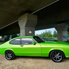 Zielony Ford Capri z lat 70. pod betonowym wiaduktem.