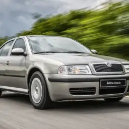 Srebrna Škoda Octavia jedzie po drodze, otoczona rozmytą zielenią. Sprawdź atrakcyjną Škoda Octavia cenę!