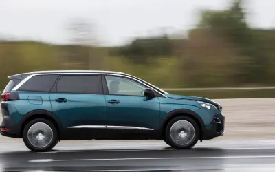 Turkusowy Peugeot 5008 2.0 HDI w ruchu, z rozmytym tłem.