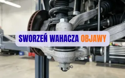 Widok na element zawieszenia samochodu. Widoczny sworzeń wahacza, sprężyna i tarcza hamulcowa. Napis "SWORZEŃ WAHACZA OBJAWY".