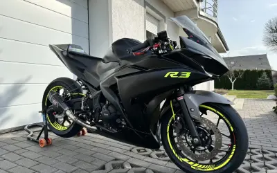 Czarny motocykl Yamaha R3 z neonowymi żółtymi akcentami, gotowy do jazdy.
