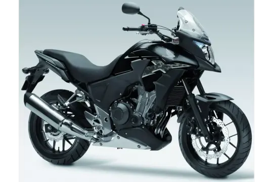 Czarny motocykl Honda CB500X z przyciemnianą szybą i chromowanym wydechem, gotowy na przygodę.