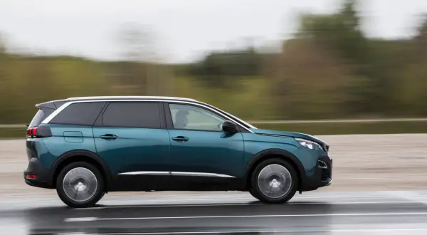 Turkusowy Peugeot 5008 2.0 HDI w ruchu, z rozmytym tłem.