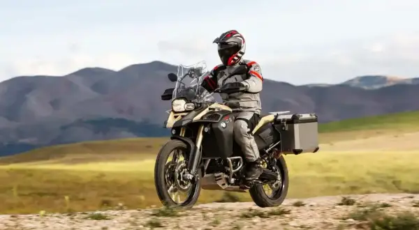 Motocyklista w pełnym rynsztunku przemierza górskie tereny na motocyklu BMW 800 GS.
