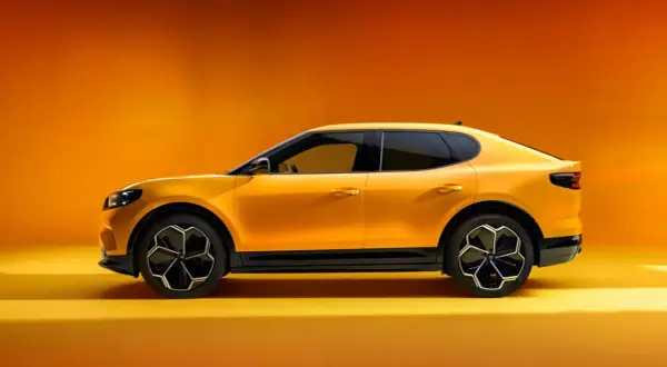 Żółty Ford Capri 2025, sportowy SUV z futurystycznym designem, prezentuje się na tle pomarańczowego gradientu.