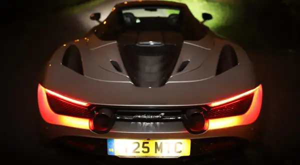 Tył srebrnego McLarena 720S nocą, z włączonymi czerwonymi światłami. Zastanawiasz się nad mclaren 720s cena?