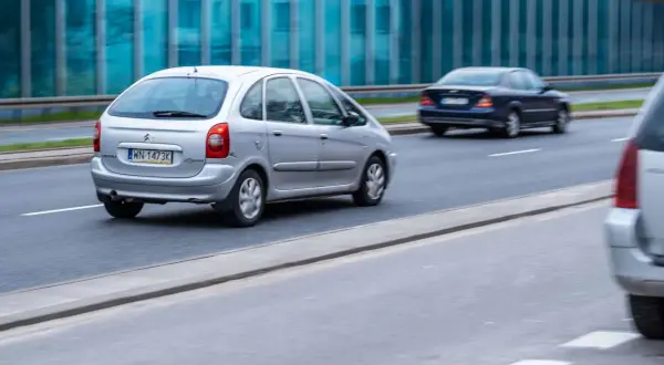 Srebrny Citroën Xsara Picasso jedzie po drodze, obok niebieski sedan.