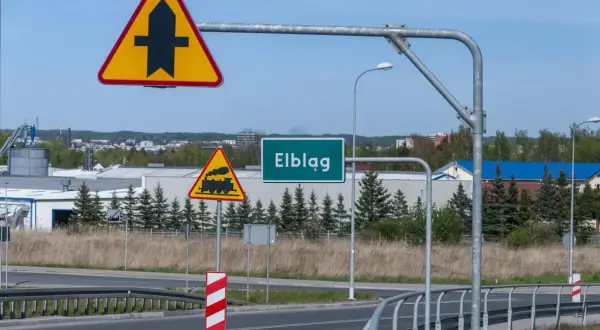 Znaki drogowe: pierwszeństwo przejazdu, przejazd kolejowy, nazwa miejscowości Elbląg.