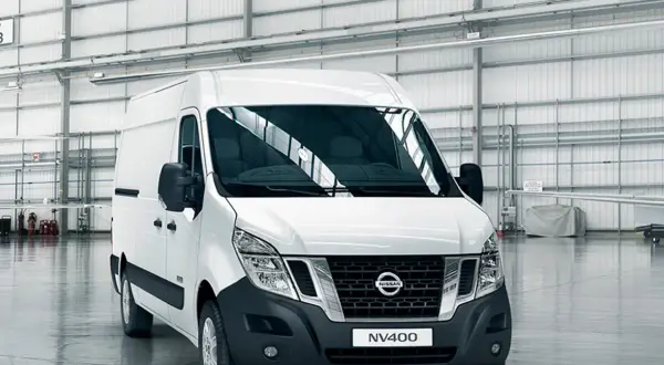 Biały van Nissan NV400 stoi w przestronnym magazynie.
