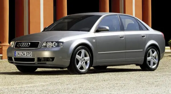 Srebrne Audi A4 B6 1.9 TDI 130KM na tle pomarańczowej ściany.