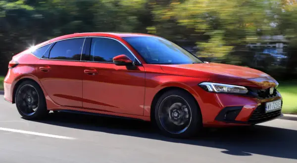 Czerwony Honda Civic 11 na drodze, z rozmytym tłem drzew.