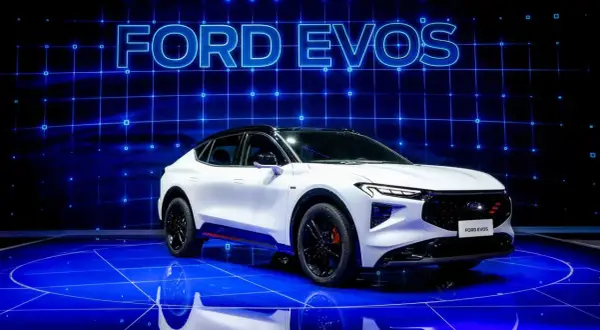 Biały Ford Evos na niebieskiej scenie z napisem "FORD EVOS" w tle.