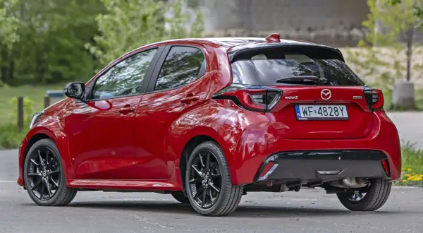 Czerwona Mazda 2 Hybrid widziana z tyłu, z czarnymi felgami i przyciemnianymi szybami.