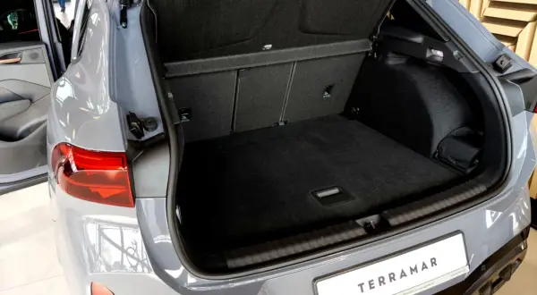 Otwarty bagażnik szarego SUV-a Cupra Terramar z widocznym wnętrzem i tablicą rejestracyjną.