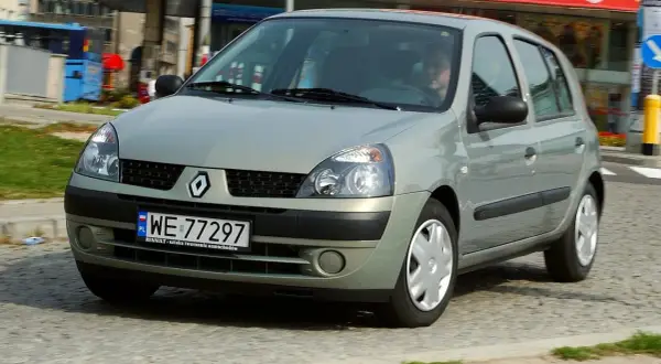Srebrny Renault Clio 2 z polskimi tablicami rejestracyjnymi WE 77297 jedzie po miejskiej ulicy.