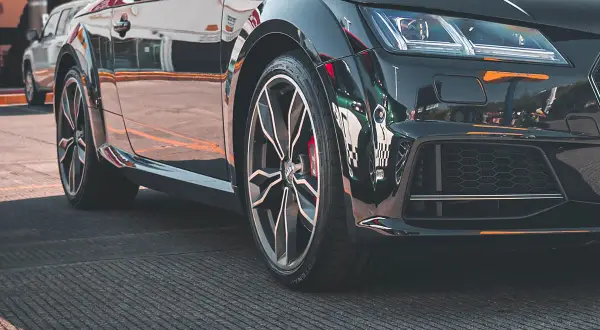 Zbliżenie na czarne, sportowe auto z felgami i oponami.