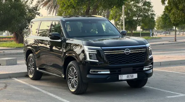 Czarny Nissan Patrol 2025 zaparkowany na tle drzew i palmy.