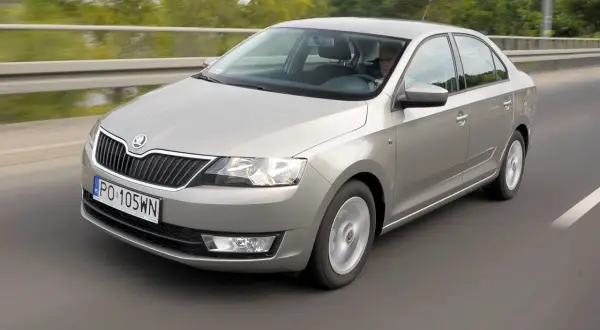 Srebrny Skoda Rapid 2018 jedzie po drodze, za kierownicą siedzi mężczyzna.