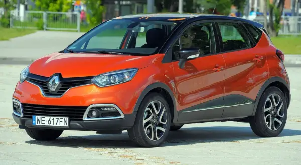 Pomarańczowy Renault Captur 2015 z czarnym dachem i pomarańczowymi akcentami, zaparkowany na placu.